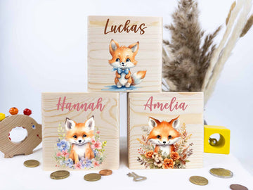 Eine hölzerne Spardose in Form eines Fuchses, mit einem Schlüssel zum Verschließen. Der Fuchs ist mit einem niedlichen Design bedruckt und lächelt freundlich